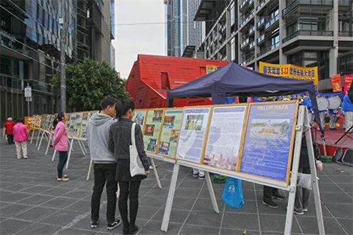 '圖4：墨爾本法輪功學員在市中心亞拉河畔的女王橋廣場（Queensbridge Square）慶祝「世界法輪大法日」。路人駐足閱讀展板。'