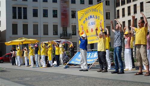 '圖1：慶祝世界法輪大法日，柏林和部份萊比錫法輪功學員在柏林布蘭登堡廣場演示功法。'