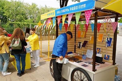 '圖11：接受真相傳單的市民來到天梯書店展位前饒有興趣地了解有關法輪功修煉的書籍。'