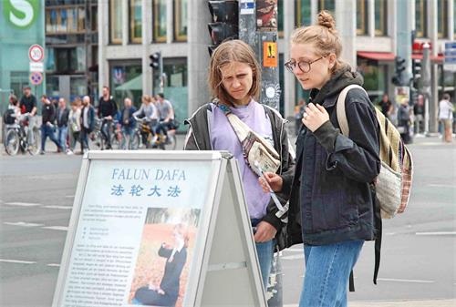 '圖5：波蘭女孩在展板前仔細閱讀，感到中共對法輪功學員的迫害觸目驚心。'