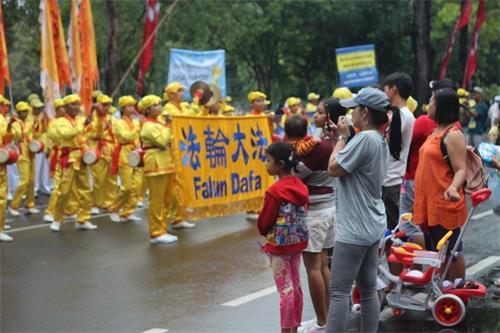 '圖6～7：眾人觀看法輪功學員遊行'