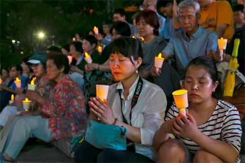 '圖13：時至今日，中共對法輪功的迫害已經持續了十九年，修煉者們手持燭光，悼念那些在迫害中失去生命的法輪功學員。'