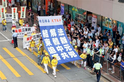 '圖9～18：約一千名法輪功學員7月22日在港島區舉行反迫害十九週年集會遊行，呼籲停止迫害、法辦元凶。遊行隊伍中大小橫幅展示中共迫害法輪功的真相，震撼許多大陸遊客。'