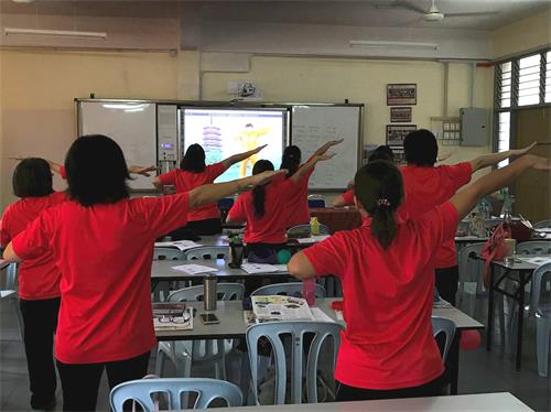 '圖2：二零一八年七月十八日，學校老師們跟隨教功錄像學法輪大法第一套功法'