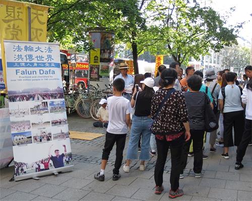 '圖2：大陸遊客路過法輪功真相展位。'