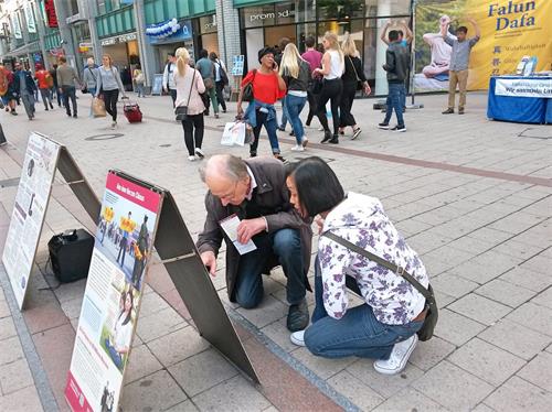 '圖5：兩位路人蹲下閱讀真相展板。'