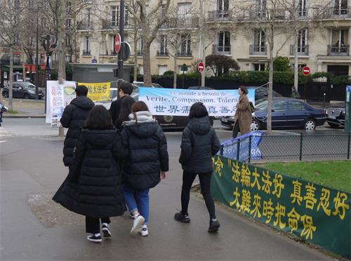 '圖1～2：艾菲爾鐵塔下，大陸遊客路經法輪功真相點，每天都有法輪功學員在那裏講真相、勸三退。'