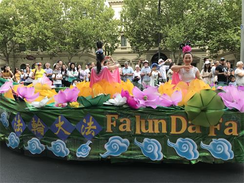 用蓮花和祥雲裝飾的花船上，仙女妝扮的學員們演示法輪功功法。