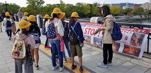 '圖10：這位教師（右）正在向學生們講解真相橫幅的內容。'