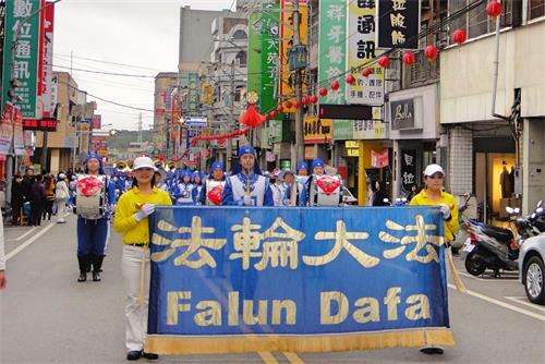 '圖1～2：近二百名法輪功學員組成的天國樂團的踩街遊行，其樂音嘹亮，路旁民眾聞聲而至，紛紛拿起手機、平版，將這支氣宇軒昂的隊伍記錄下來。'