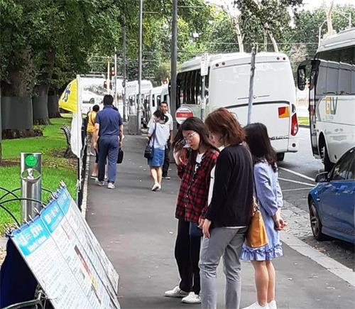 墨爾本市中心著名景點費茨羅伊公園是大陸遊客了解法輪功真相的窗口。圖為中國新年期間，大陸客在閱讀擺放在公園入口處的大法真相展板。