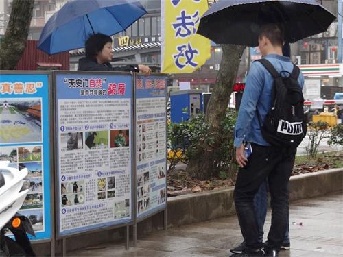 '圖1：遊客雨中了解法輪功真相。'