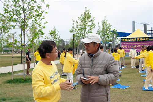 '圖3：法輪功學員在向越南裔居民楚先生（Loc Chu）在向民眾介紹法輪功功法。'