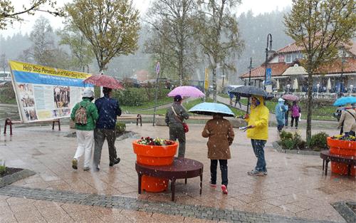 圖1： 在風雪中，德國法輪功學員Yansi對大陸遊客用中文說：中國人，德國歡迎你們，請記住法輪大法好！