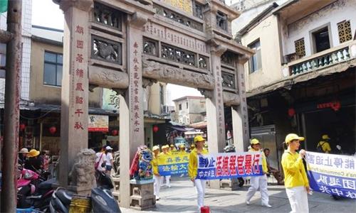 '圖2：法輪功學員手持「制止中共非法活摘器官暴行」等橫幅，行經邱良功母節孝坊。'