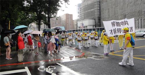 '圖11～13：中國大陸遊客冒雨觀看法輪功遊行。'