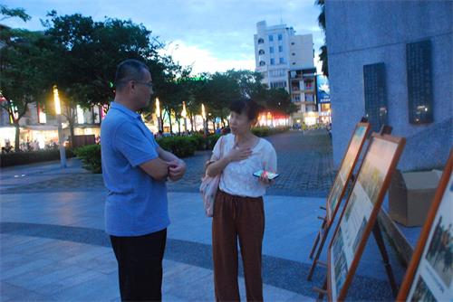 '圖9：法輪功學員徐小姐向看真相展板的遊客解釋'