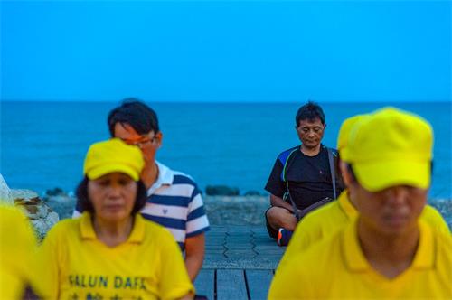 '圖7：台東法輪功反迫害燭光悼念，路過民眾主動與法輪功坐在一起，表達支持。'