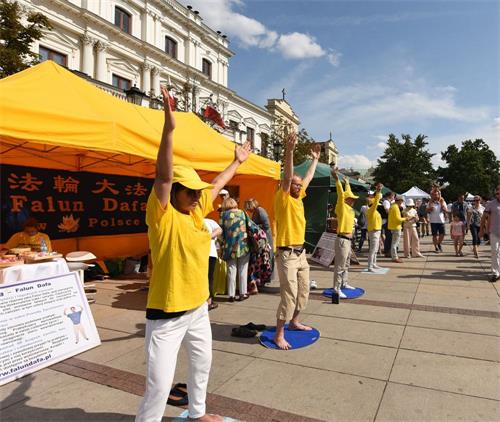 '圖1：法輪功學員向過往民眾展示五套功法'