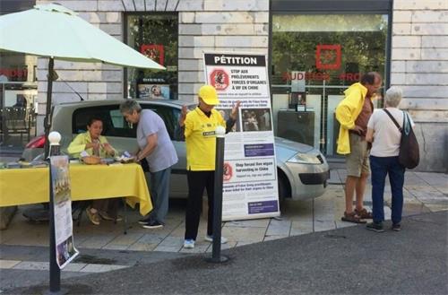 '圖2～3：法輪功學員在貝藏松市設置展台，傳播真相。'