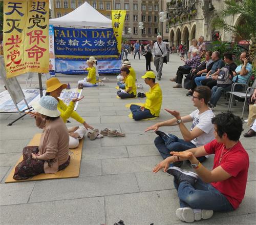 '圖3：有人當場跟法輪功學員學煉功法。'