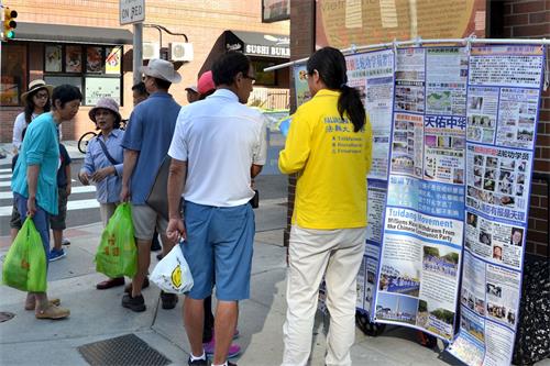 '圖2：民眾在觀看法輪功真相展板，了解真相。'