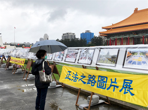 '圖12：李小姐在「正法之路圖片展」前仔細閱讀法輪大法弘傳世界的盛況。'