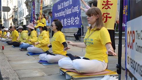 '圖6：二零二零年七月二十日， 英國法輪功學員尤麗雅（Yulia，右）參加在倫敦中共使館前的集體煉功'