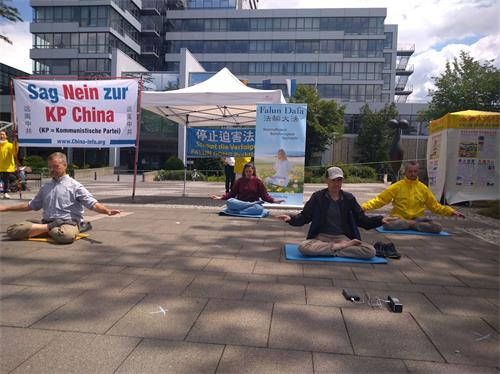 '圖9～10：二零二零年七月十一日星期六，部份法輪功學員在德國愛爾蘭根市（Erlange）市政廳廣場舉辦了講真相活動。圖為學員在煉功。'