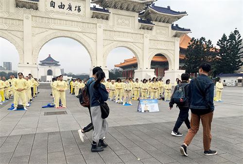 '圖1～2：被疫情籠罩的台北市，法輪功學員集體煉功散發的祥和能量場吸引前來自由廣場的遊客駐足拍照，拍下這珍貴的場面。'