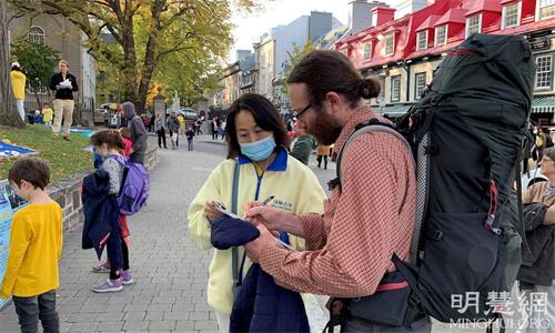 '圖7：人們在呼籲反迫害的徵簽信上簽名，表達對法輪功學員的支持'