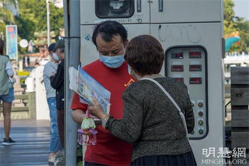 '圖9：一位常在蓮池潭四週步行運動的餐飲業廚師，被純淨的煉功畫面吸引駐足觀看，並表示他回去會再上網深入了解法輪功。'