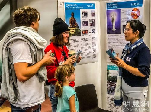 '圖2～3：法輪功學員的展台前參觀者們絡繹不絕，學員向與會者介紹以修煉真、善、忍為原則的法輪功。'