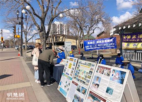 '圖1～2：二零二一年四月二十四日，加拿大埃德蒙頓部份法輪大法學員在威爾伯特﹒麥金太爾博士公園傳播真相，紀念四﹒二五和平上訪二十二週年。了解真相後的市民簽名反對中共迫害法輪功。'