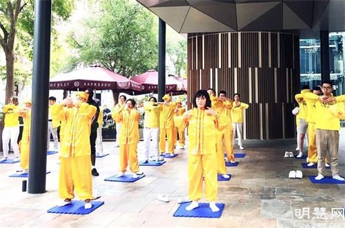 '圖8：法輪功學員在市中心向居民展示法輪大法五套功法'