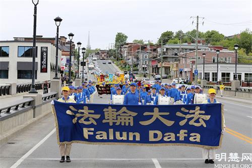 '圖1：2021年5月30日，法輪功學員在加拿大魁北克省捨布魯克市（Sherbrooke）舉行遊行活動，慶祝世界法輪大法日暨法輪大法（法輪功）弘傳世界29週年。'