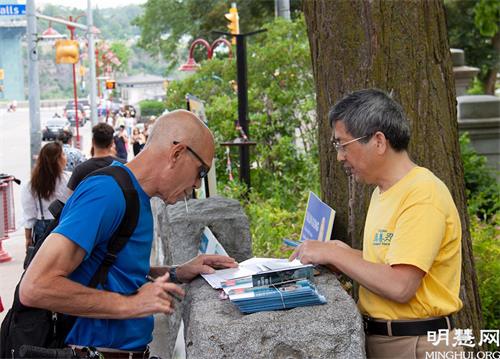 '圖3：遊客在尼亞加拉大瀑布煉功點了解法輪功真相並簽名支持反迫害。'