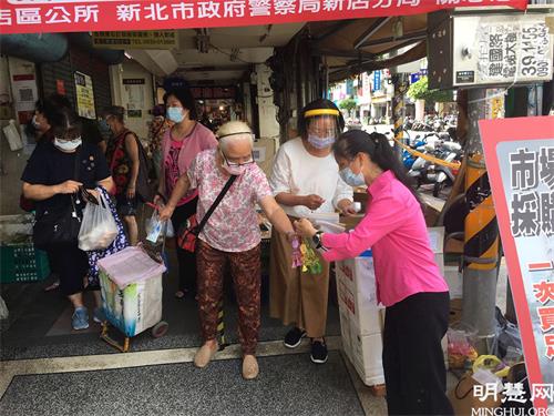 '圖1～2：法輪功學員在市場門口為民眾量體溫並藉機傳遞真相資料和小蓮花'