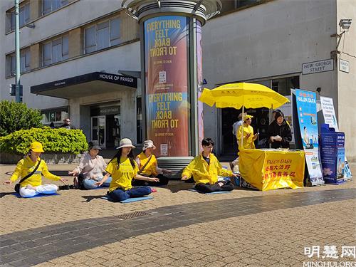 圖2：法輪功學員在普利茅斯（Plymouth）市中心設立真相點。圖為法輪功學員正在演示功法。