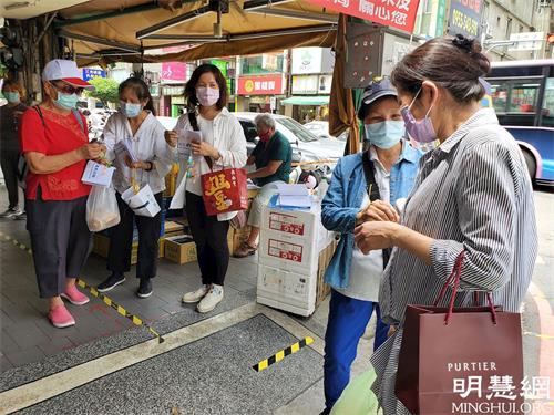 '圖1：法輪功學員在傳統市場出入門口設攤協助單位執行實聯制，並講真相及送上帶有真善忍信息的蓮花與真相資料。'