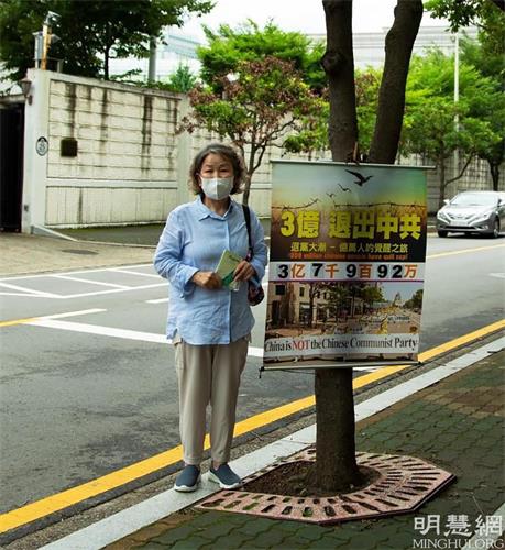 '圖1：駐釜山中國總領事館對面，南女士每天在固定的地點掛好真相橫幅，向中國人發放真相資料。'