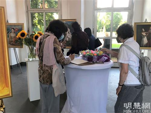 '圖2：一位參觀者在美展留言簿上留言。'