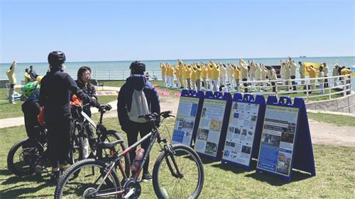 '圖4-5：二零二二年五月七日，大芝加哥地區部份法輪功學員在密西根湖畔集體煉功，民眾主動前來了解法輪功。'